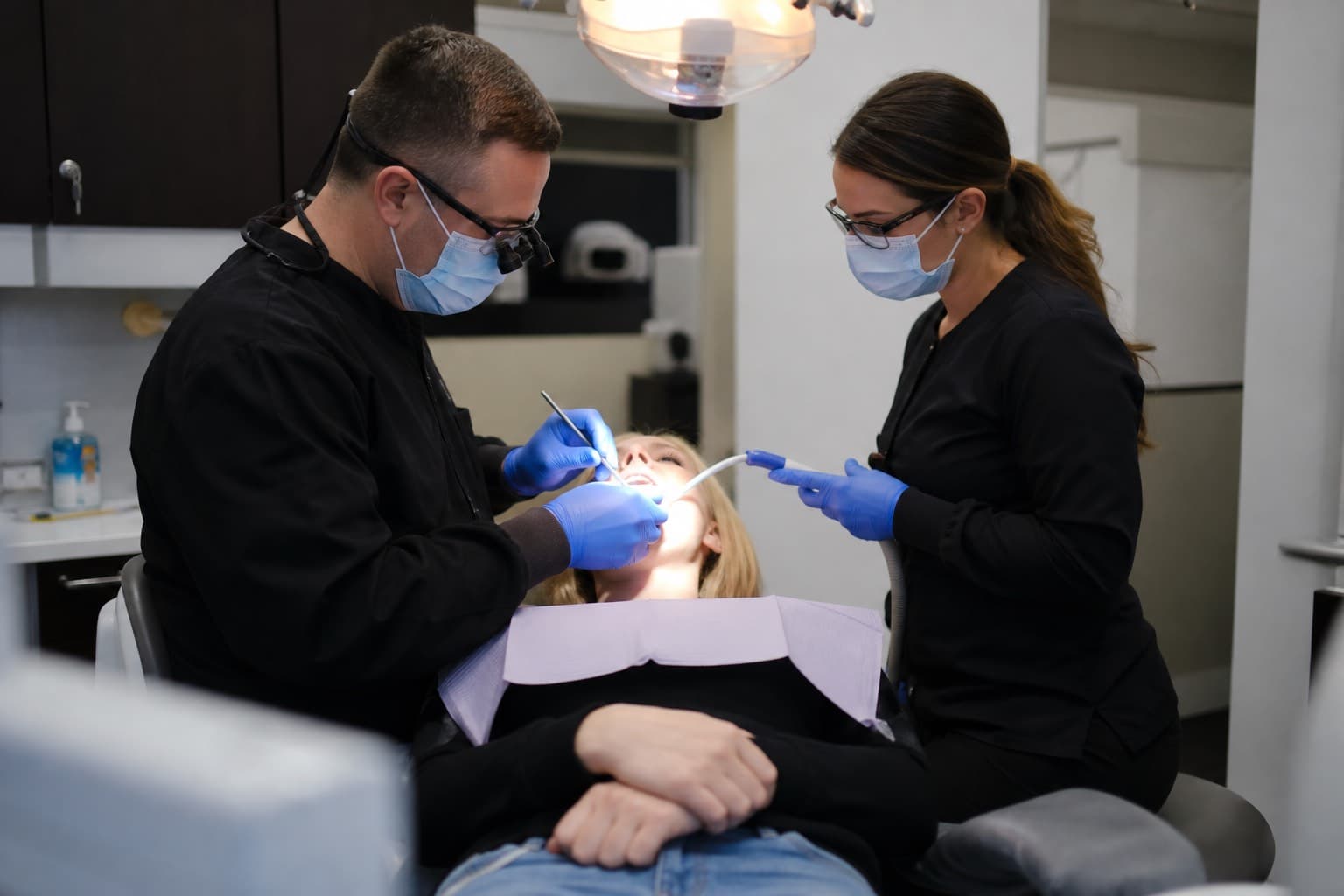 Dentist and assistant treating a reclined patient